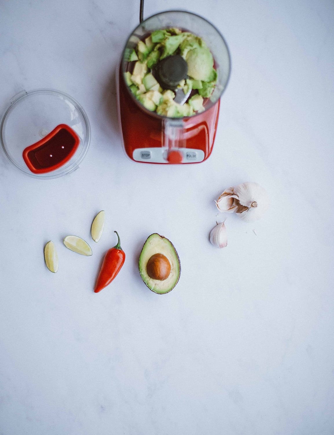 Red food processor next to avocado and peppers