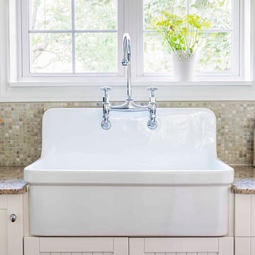 Large white porcelain kitchen sink and granite stone countertop under window