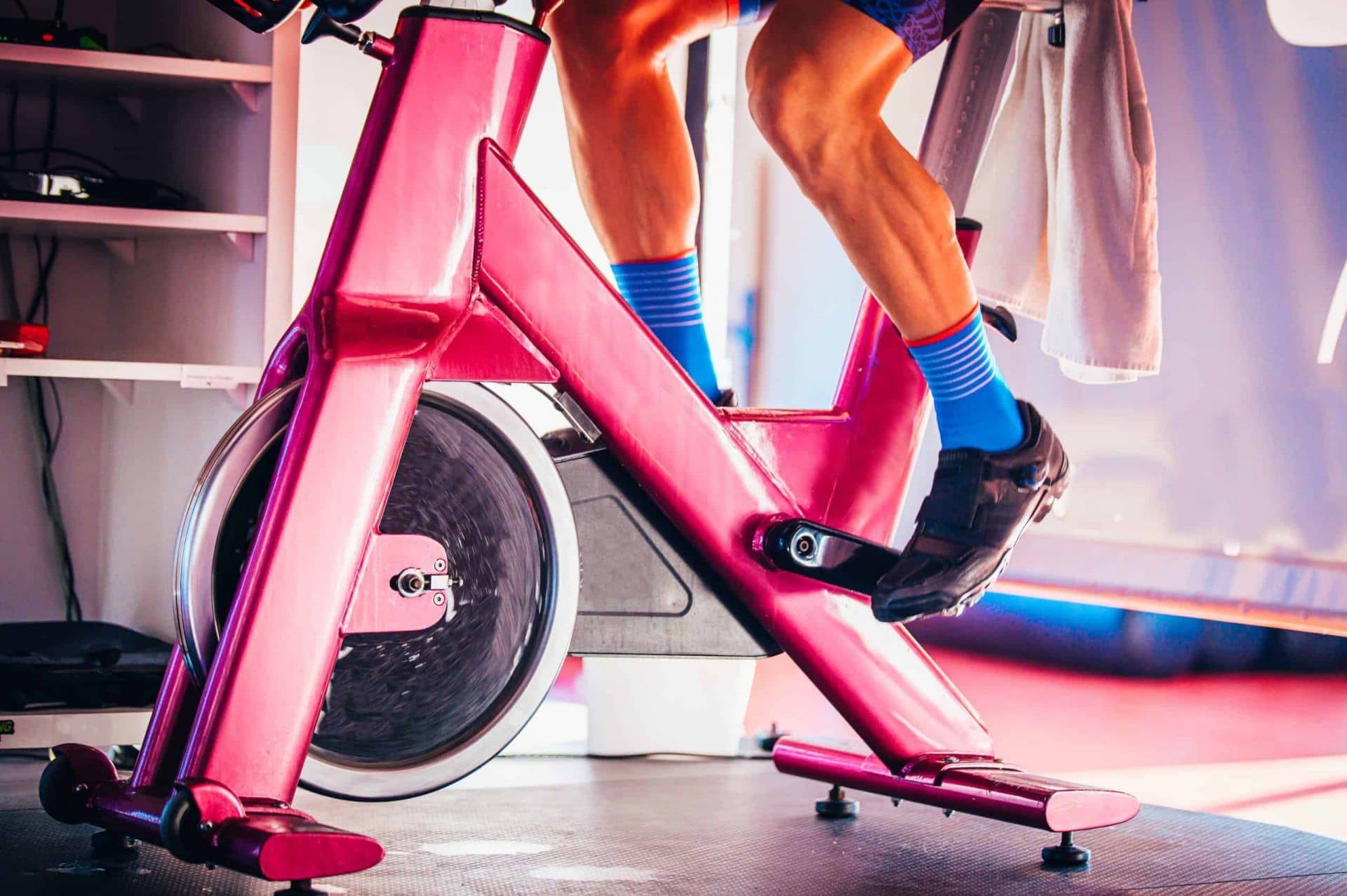 Image of a man in blue socks on a pink spin bike