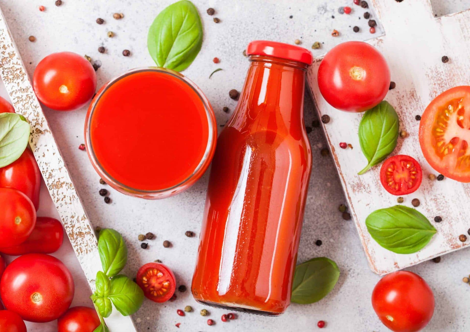 Bottle of fresh organic tomato juice with fresh tomatoes basil and pepper on a stone table
