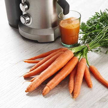 Juicer with a glass of fresh carrot juice