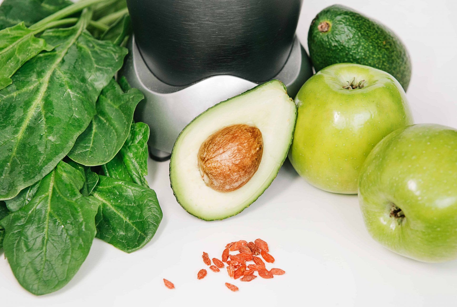 fitness blender with a set of healthy products, apple avocado spinach on a white background