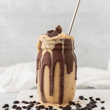 Image of a chocolate coffee milkshake in a mason jar with metal straw on a granite table