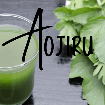 glass of aojiru juice next to green vegetables