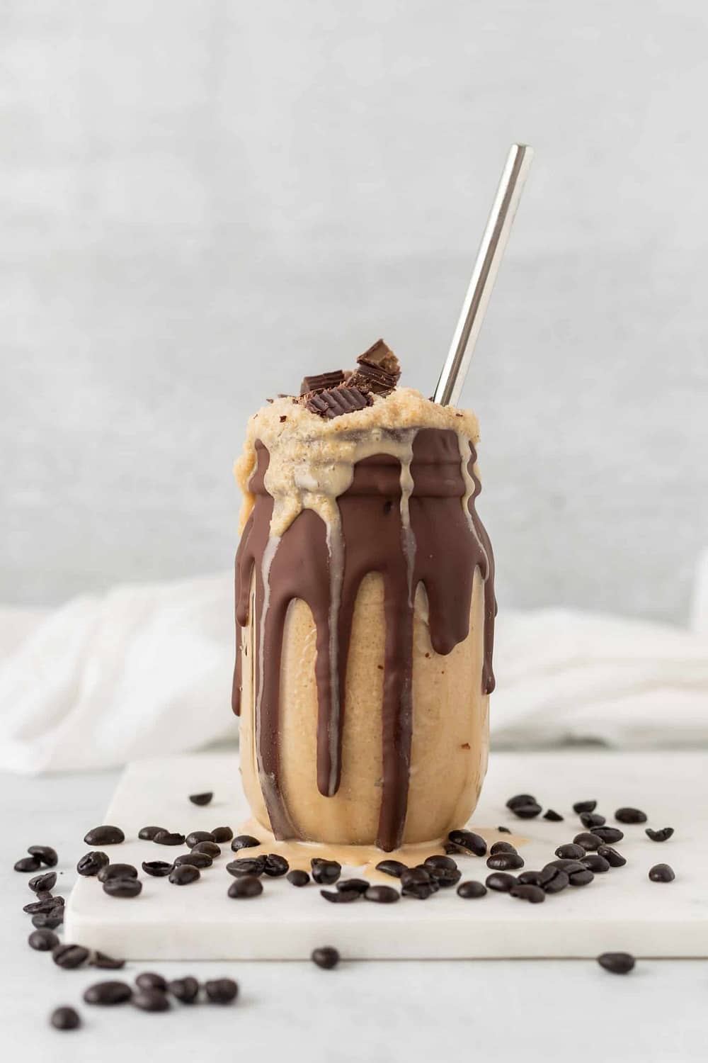 Image of a chocolate coffee milkshake in a mason jar with metal straw on a granite table