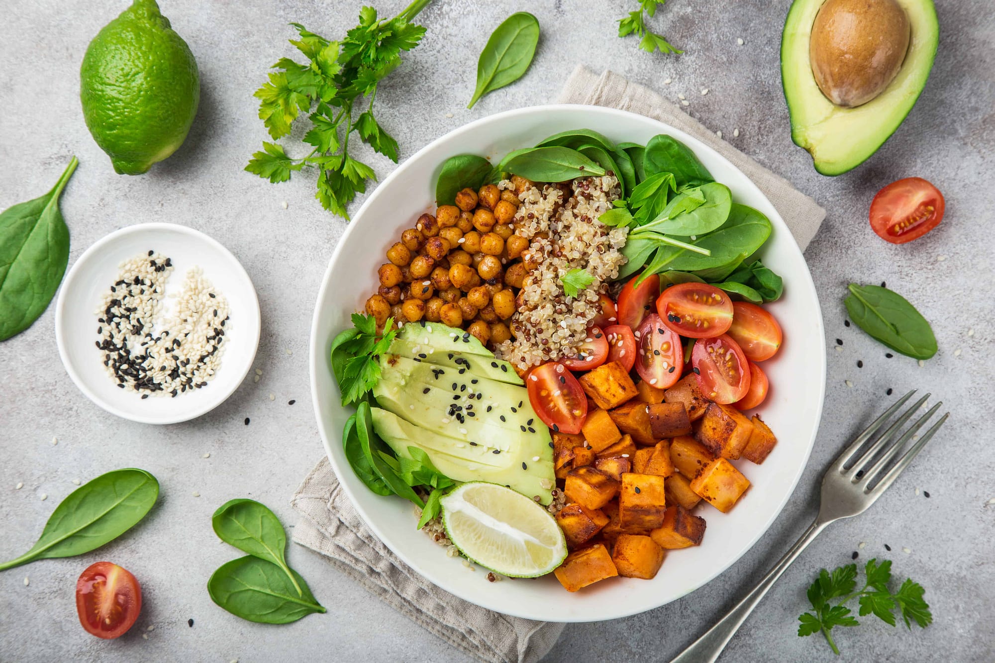 Transitioning to a plant-based diet with a healthy vegetable bowl of avocado, quinoa, sweet potato, tomato, spinach, and chickpeas 