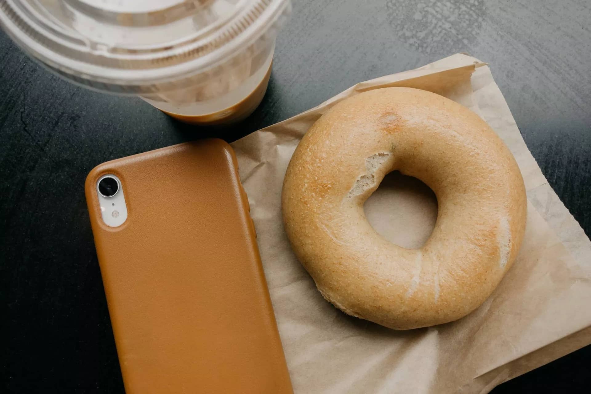 Bagel next to coffee and phone