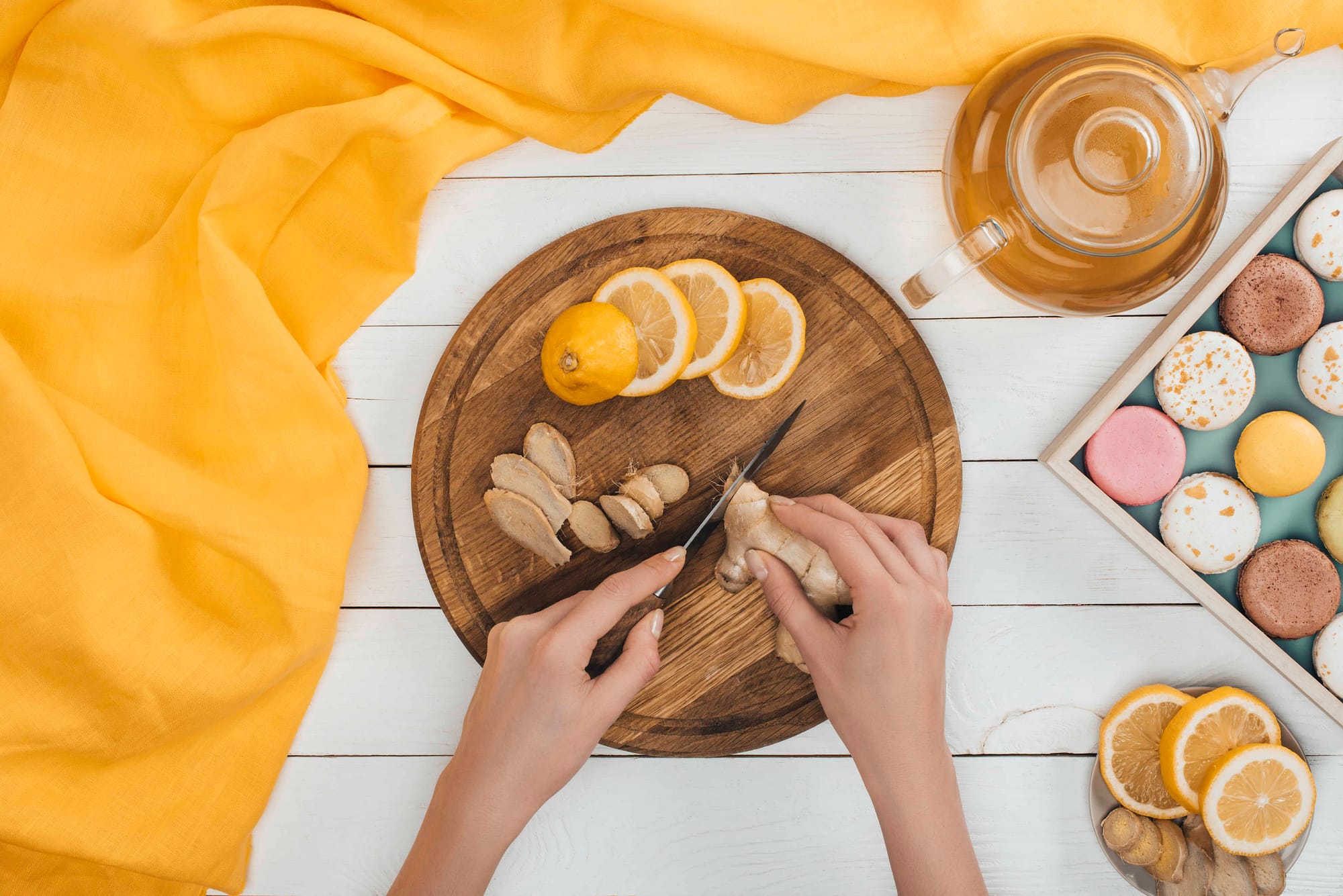 woman cutting ginger and lemons on cutting board