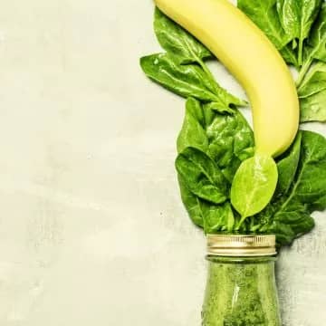 Spinach green smoothies in a glass bottle, gray background