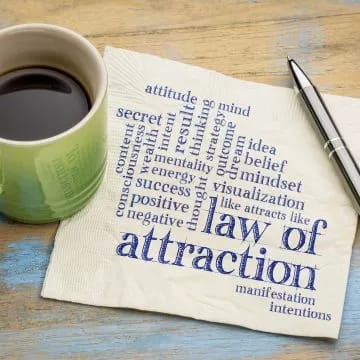 law of attraction printed on a napkin next to a cup of coffee
