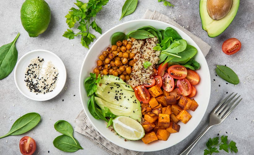 Transitioning to a plant-based diet with a healthy vegetable bowl of avocado, quinoa, sweet potato, tomato, spinach, and chickpeas